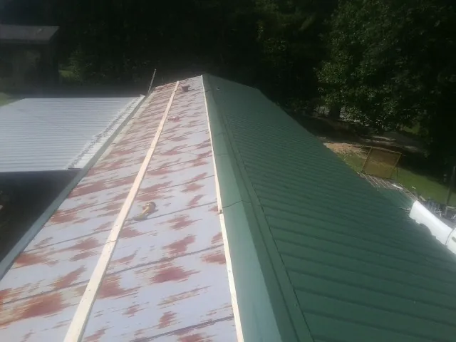 Old rusted panels beside newly installed green metal roofing — Wind Damage Roof Repair by Roofing Brothers in Raritan