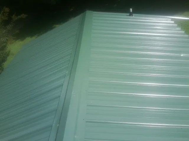 New green metal panels meeting at the ridge of a roof — Flat Roof Repair work by our crew in Raritan