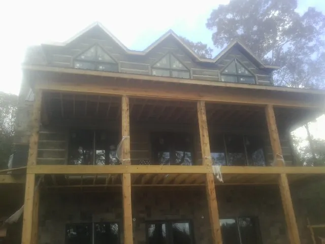 Dormers and porch framing on a large log home under construction — Roof Coating work by our crew in Raritan