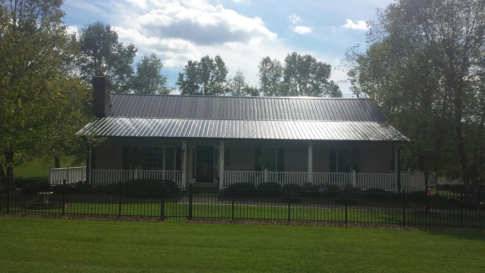 Gray metal roof on a brick ranch with a full width front porch — Gutter Guard Installation work by our crew in Raritan