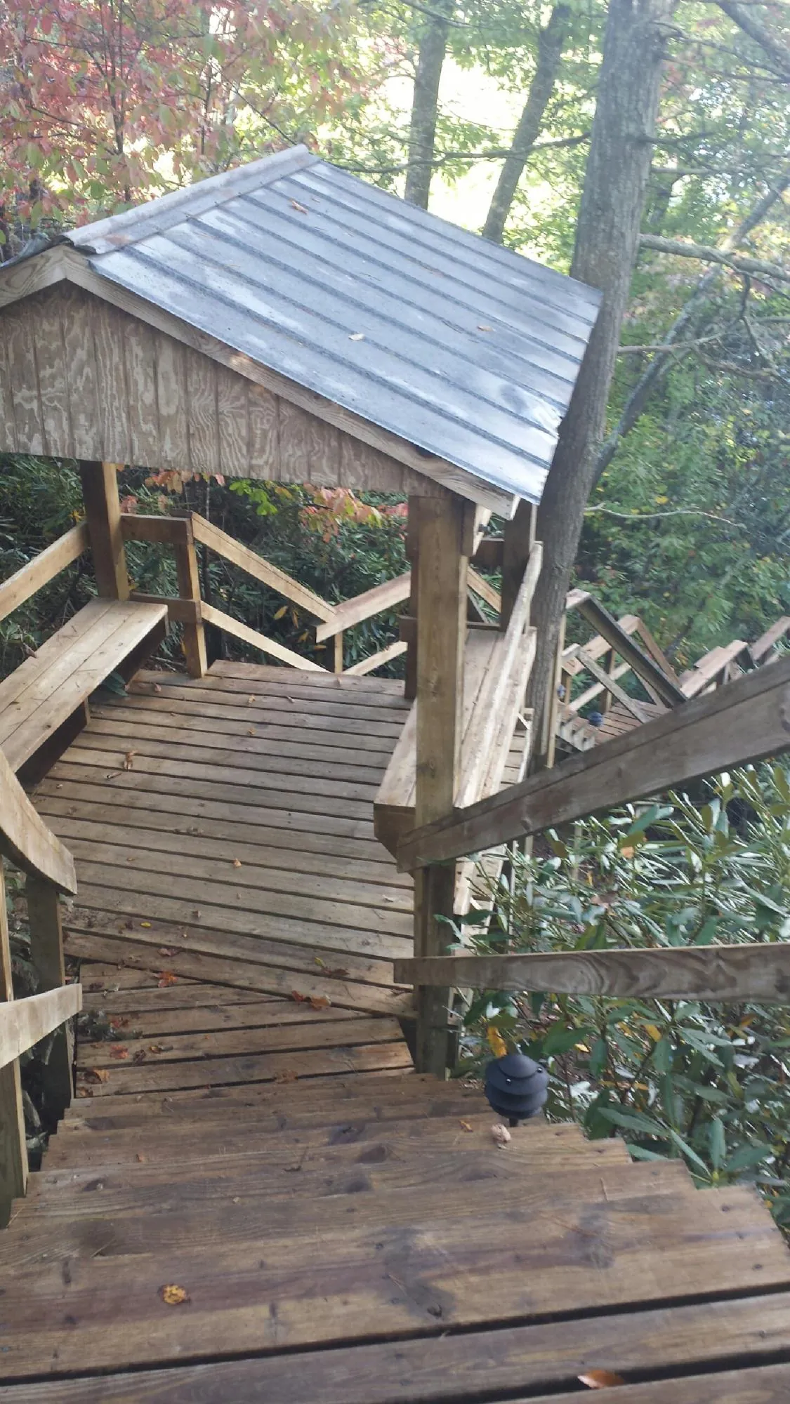 Metal roofed shelter over wooden steps on a wooded walkway — Skylight Repair & Installation work by our crew in Raritan