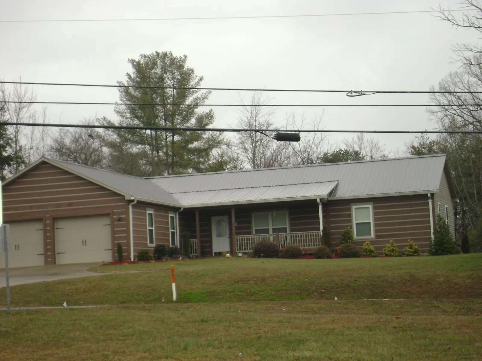 Gray metal roof on a log sided ranch home with a front porch in Raritan