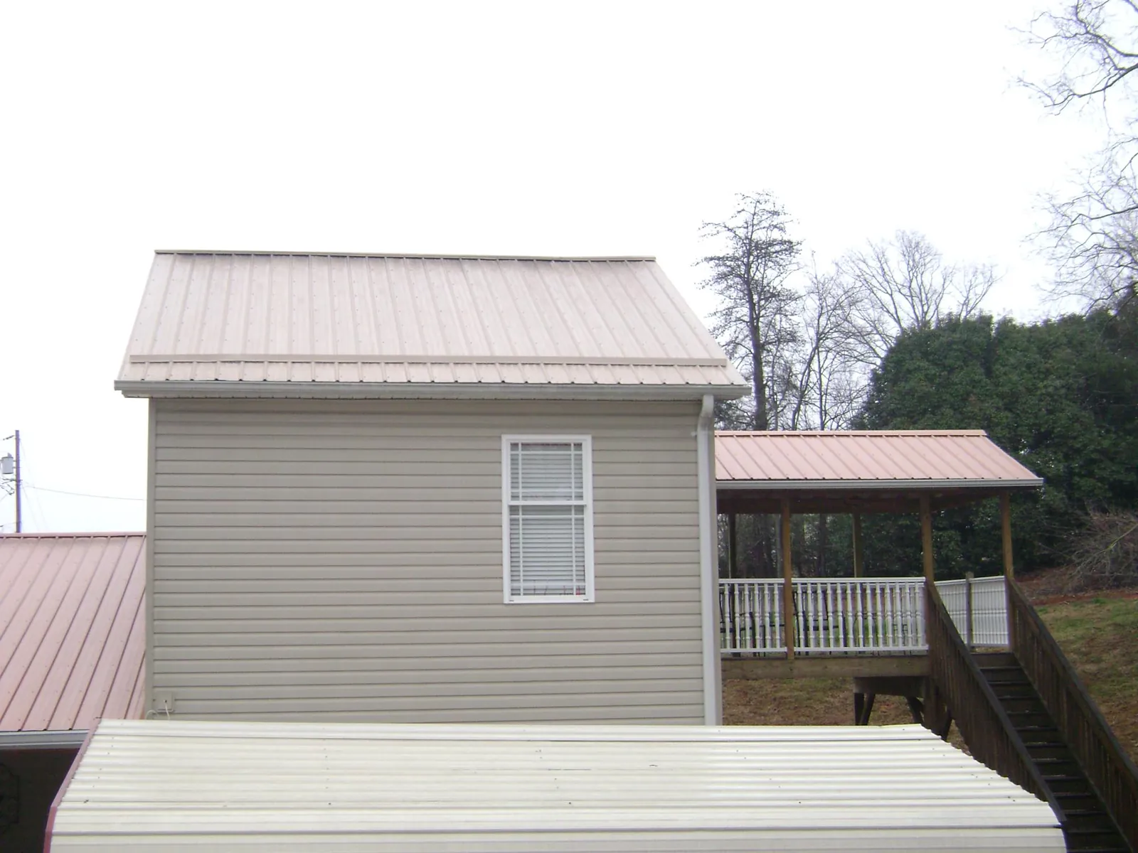Tan metal roofs on a two story addition and attached porch, from a Roof Replacement job in Raritan