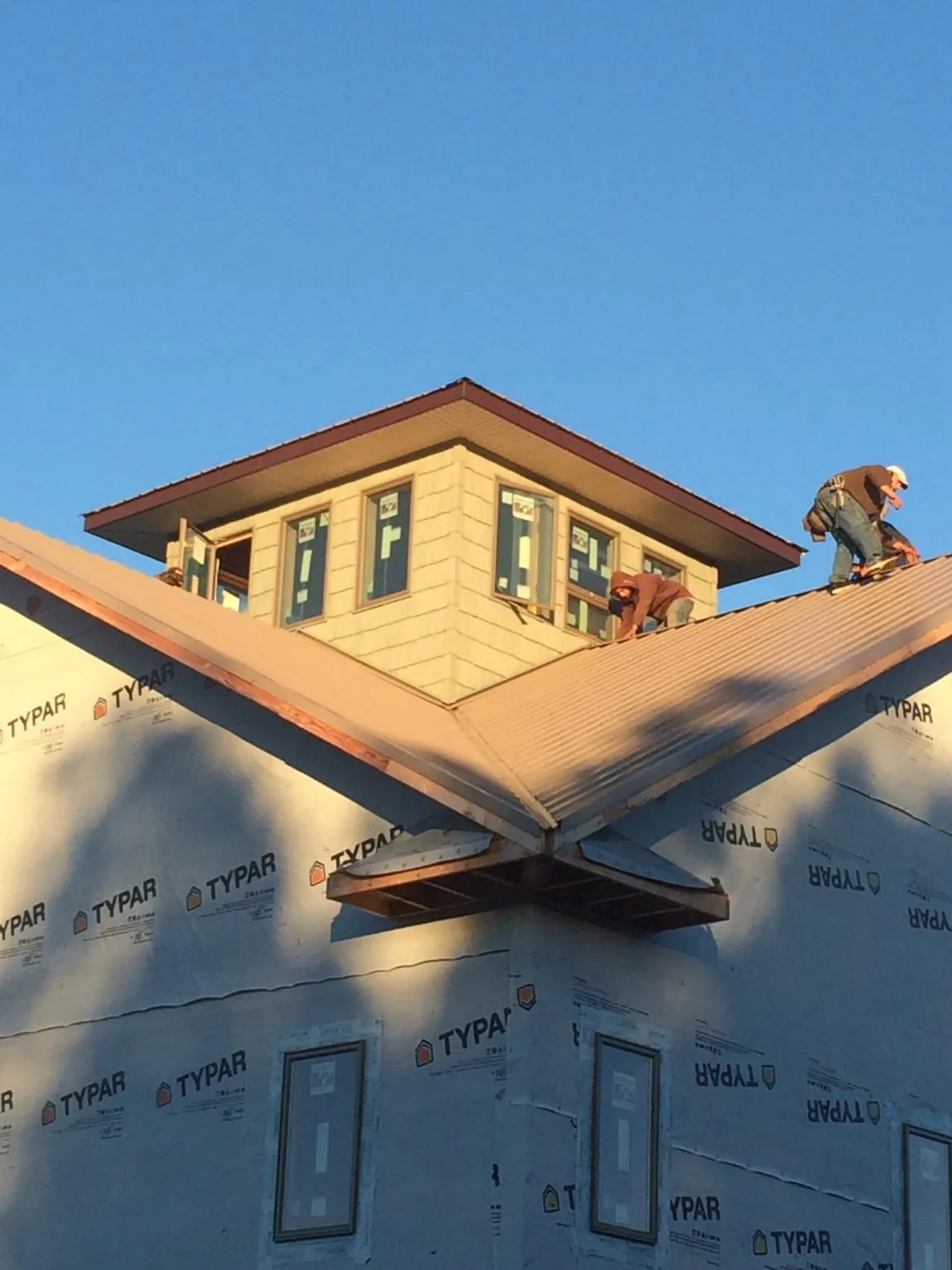 Roofers working around a rooftop cupola on a new metal roof at sunset — Roof Waterproofing in Raritan by Roofing Brothers